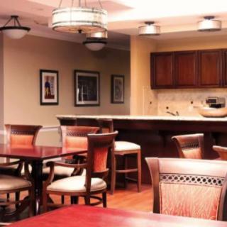 A cozy dining area with wooden tables and chairs, adjacent to a kitchen space.