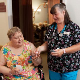 A nurse providing medication assistance to a patient in a caring environment.