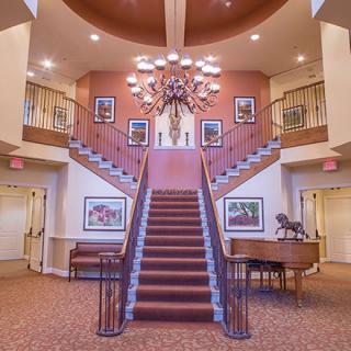 A grand lobby with a central staircase and elegant chandelier.