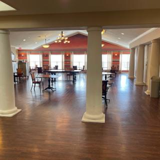 A spacious lobby area featuring columns, wooden flooring, and ample natural light.