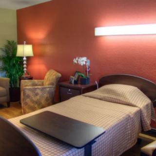 A well-furnished hospital room with a bed, side table, and comfortable seating.