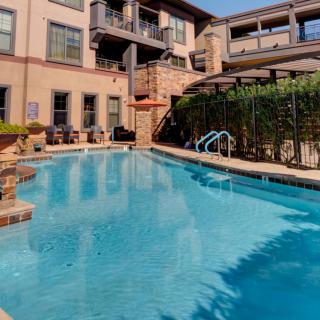 A serene swimming pool area within an apartment complex on a sunny day.
