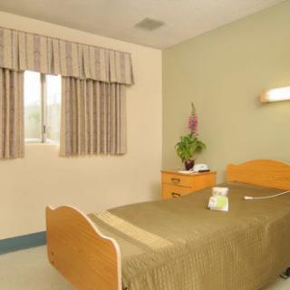 A simple and minimalist bedroom with a single bed, a small dresser, and a window with curtains.