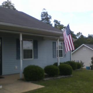 A suburban house with an American flag displayed in the front yard.