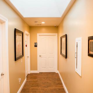 A well-lit hallway featuring framed art and multiple doors.