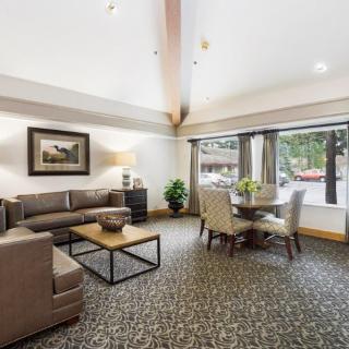 A modern living room featuring a comfortable sofa, coffee table, and dining area with a large window providing ample natural light.