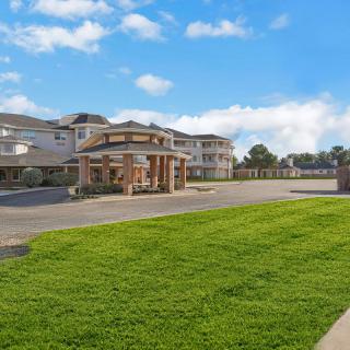 A large building with a well-maintained lawn under a partly cloudy sky.
