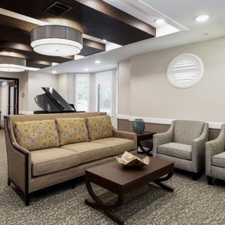 A modern living room featuring a sofa, chairs, coffee table, and a grand piano in the corner.