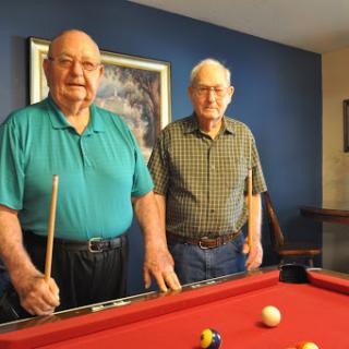 Two friends enjoying a game of billiards together.