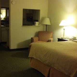 A cozy hotel room featuring a bed, lamp, and a comfortable chair.