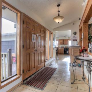A well-lit hallway with wooden doors and tiled flooring leading to a kitchen area.