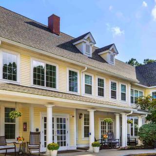 A large residential house with a porch and columns, surrounded by a garden.