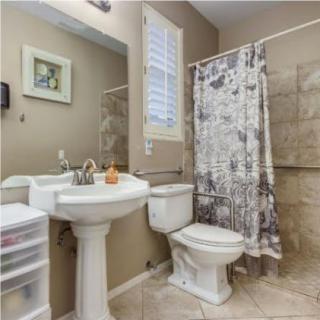 A clean and tidy bathroom with a pedestal sink, toilet, and a shower curtained bathtub.