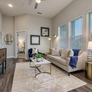 A modern and minimalist living room with bright natural lighting, featuring a comfortable sofa, a chic coffee table, elegant decor, and wood flooring.