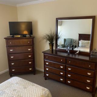 A cozy bedroom setup featuring a dresser with a mirror and a television atop another drawer unit.