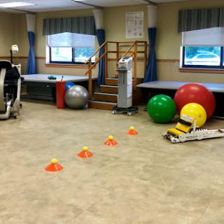 A physical therapy room equipped with exercise balls, cones for agility training, and various fitness equipment.