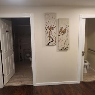 A hallway with two open doors leading to bathrooms and wall art between them.