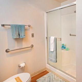 A modern and clean bathroom with a shower, toilet, and neatly arranged towels.