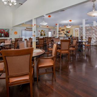 A spacious dining area with neatly arranged tables and chairs, featuring a wooden floor and elegant decor.