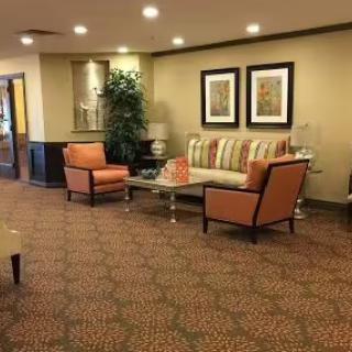 A cozy lobby seating area with orange chairs, a striped sofa, and a coffee table.
