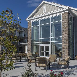 A modern building with large windows and outdoor seating on a sunny day.