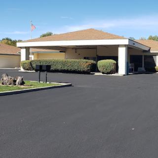 A view of a well-maintained residential building with a spacious parking area and landscaped surroundings.
