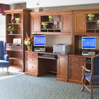 A well-organized office space with wooden furniture, featuring two computers and a printer.
