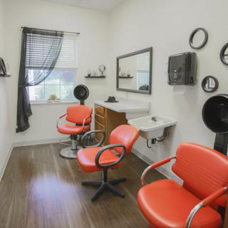 A cozy hair salon with orange chairs and modern decor.