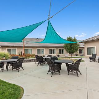 A courtyard with tables and chairs under shade sails.