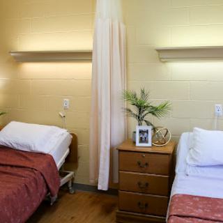 A shared hospital room featuring two neatly made beds with bedside tables.