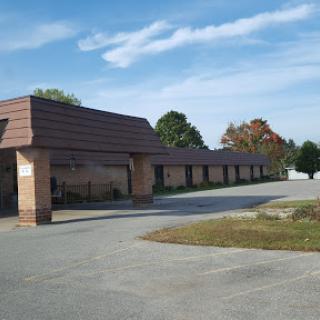 A view of a commercial building with a brown tiled roof, set against a clear blue sky and surrounded by greenery.