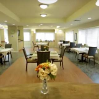 A well-lit dining room featuring neatly arranged tables and chairs, with a floral centerpiece.