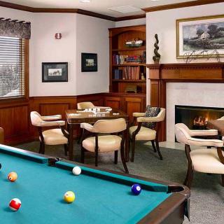 Cozy game room with a pool table, fireplace, and seating area.