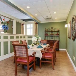 A cozy dining room with green walls and wooden furniture, featuring a table set for a meal.