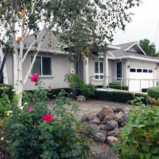A charming residential home with a well-maintained front yard featuring colorful flowers and shrubs.