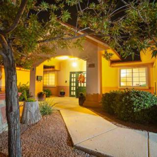 A warmly lit house entrance at night with a surrounding landscape.