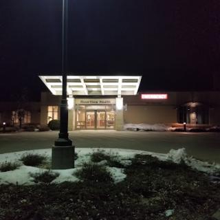 The illuminated entrance of a building at night, surrounded by snow.