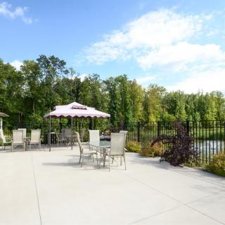 A serene outdoor patio area with tables, chairs, and umbrellas surrounded by lush greenery.