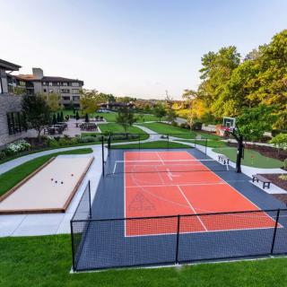 An outdoor recreational area featuring a tennis court and lush green surroundings at a resort.