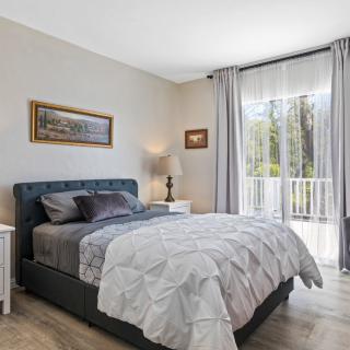 A cozy bedroom with a large bed, soft lighting, and natural light from the window.