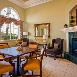 A cozy living room with a dining area and fireplace, featuring elegant furniture and large windows.