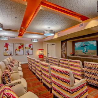 A cozy theater room with patterned seating and vibrant artwork on the walls.