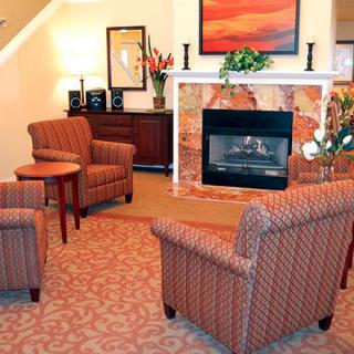 A cozy living room with a central fireplace, surrounded by comfortable chairs and elegant decor.