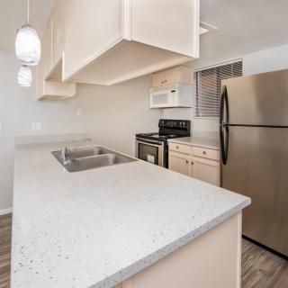 A modern kitchen with a sleek countertop, stainless steel appliances, and pendant lighting.