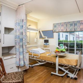 A well-equipped hospital room with a patient bed, medical equipment, and a window providing natural light.