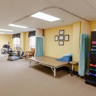 A rehabilitation therapy room equipped with exercise machines and a treatment table.