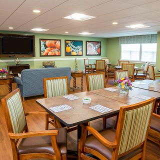 A cozy dining area with tables, chairs, wall art, and a television.
