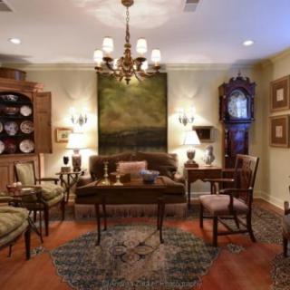 A traditional living room featuring antique furniture, a chandelier, and classic decor elements.
