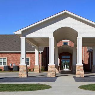 A modern building with a prominent covered entrance supported by columns.
