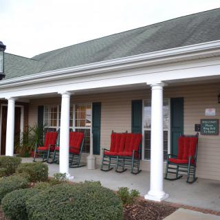 A building with a porch featuring red rocking chairs and white columns.